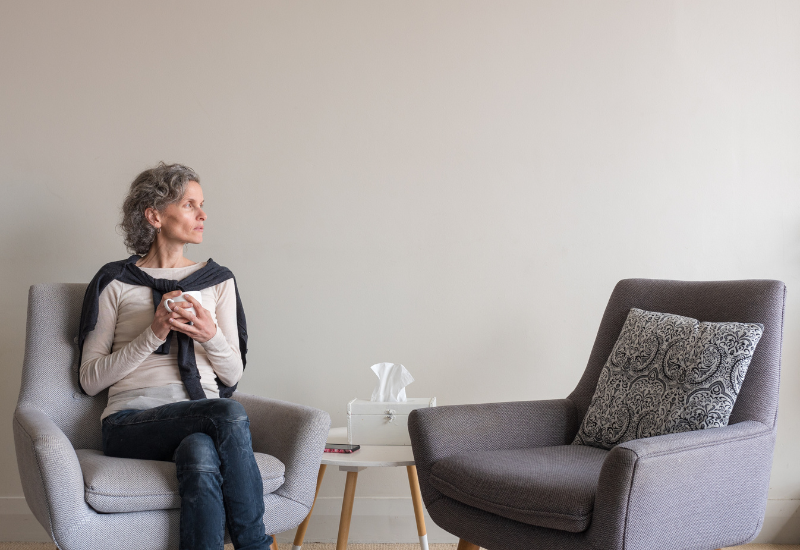 Person sitting alone in a quiet room, reflecting the emotional and physical betrayal trauma symptoms after trust is broken