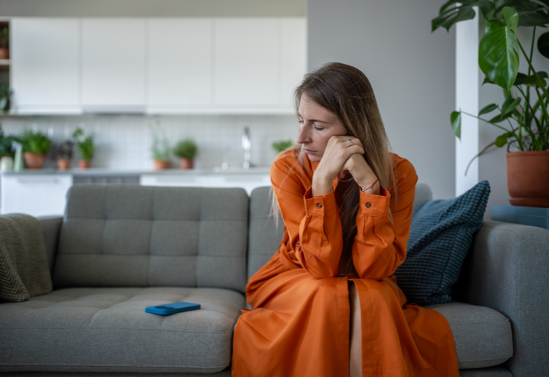 Person sitting thoughtfully on a couch, reflecting emotional strain and codependency in relationships